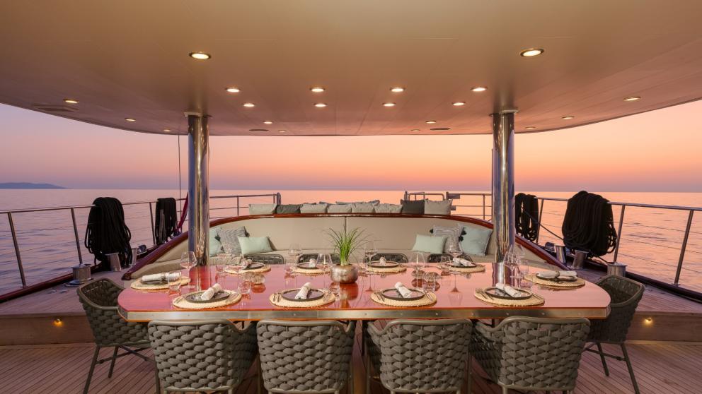 Der Tisch ist für das Abendessen im Aussenbereich gedeckt bei malerischem Sonnenuntergang.